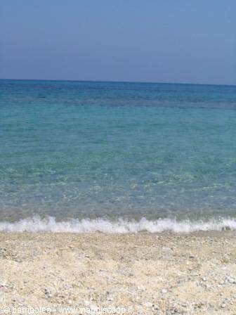 Clear waves washing over sand, turquoise sea under blue sky