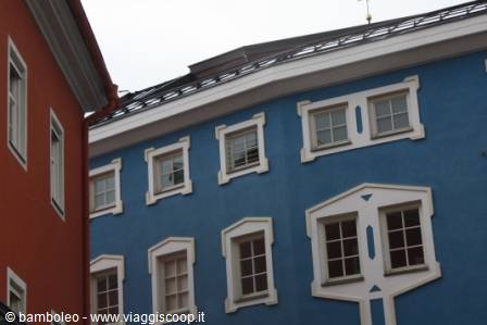 Blue facade with framed white windows beside an orange building