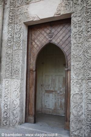 Romanesque carved stone portal with wooden door and round arch