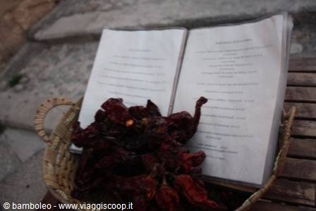 Dried red chili peppers in a wicker basket next to a menu
