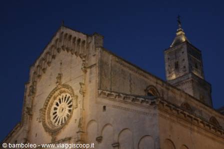 Matera cathedral stone facade, rose window and lit bell tower at dusk