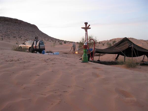 Hookah on the sand beside a Bedouin tent and an off-road vehicle