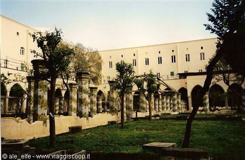 Cloister with majolica-decorated columns and trees in the garden