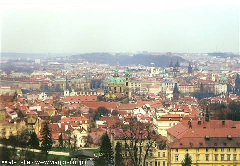 Prague: red rooftops and green dome of St. Nicholas under grey sky