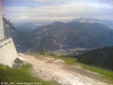 Chairlift on grassy mountain, village nestled in the valley below