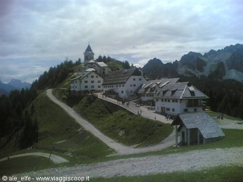 Mount Lussari sanctuary with bell tower, wooden houses and gravel path