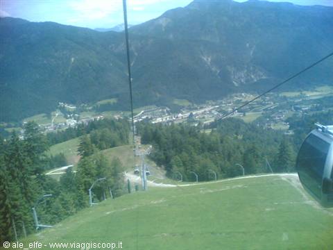 Cable car cabin above the green slope, village in the valley below
