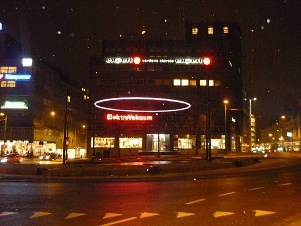 Snowy Oslo square at night, ElektroVakuum neon signs on a dark building