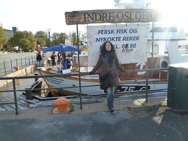 Woman beside a wooden fishing boat at Indre Oslofjord harbor, Oslo