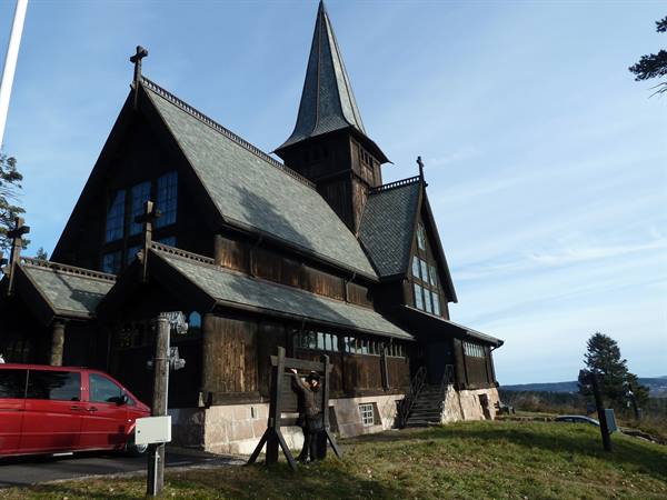 Holmenkollen Chapel, dark wooden church with spire, red van parked outside