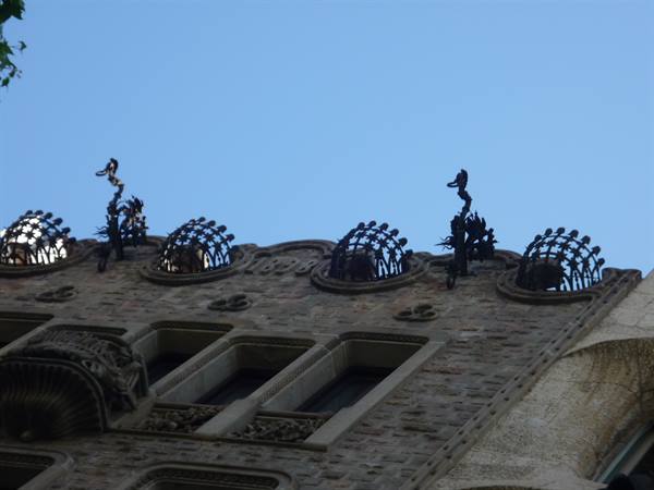 Guglie e cupole di ferro battuto in cima a una facciata modernista di Barcellona