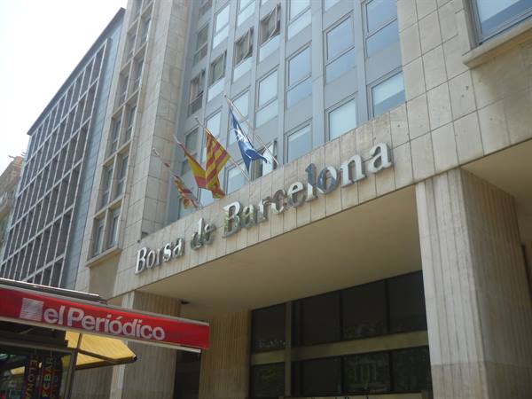 Facciata in pietra della Borsa de Barcelona con insegna metallica e bandiere