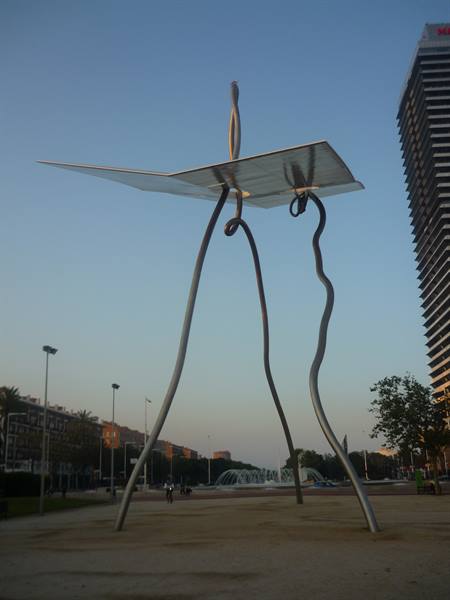 Steel needle-and-thread sculpture on urban square at dusk