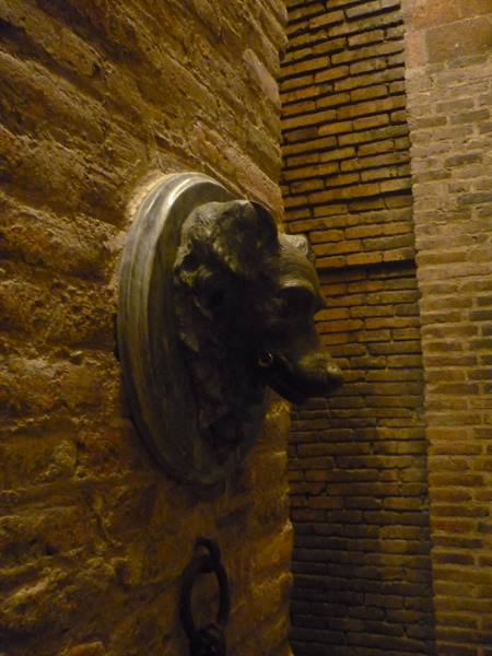 Bronze dog head on marble medallion, brick wall