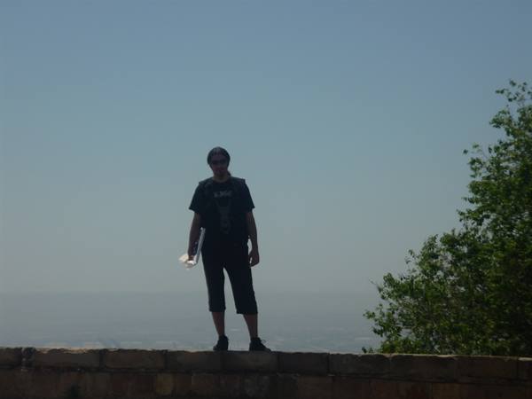 Tourist standing on a stone wall, blue skies and green trees