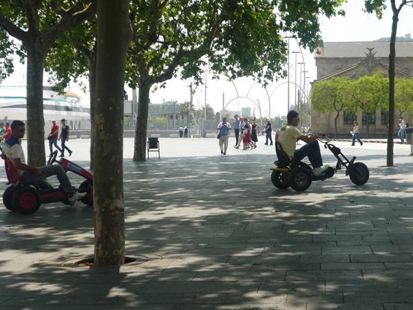 Boys riding pedal karts under plane trees at Moll de la Fusta, Barcelona