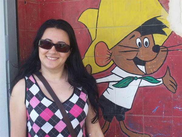 Woman with sunglasses next to a painted Speedy Gonzales cartoon mural