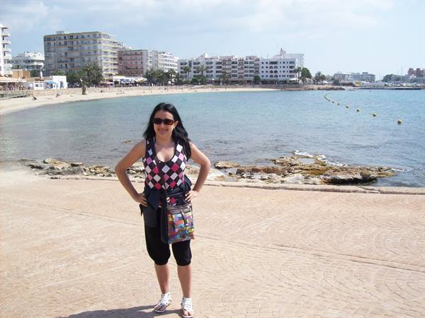 Woman in sunglasses poses on the promenade in front of a bay lined with hotels