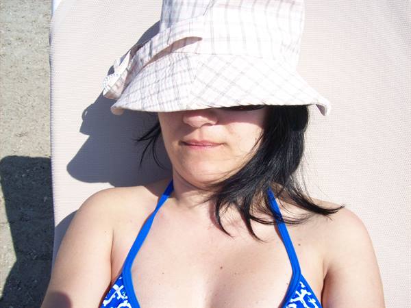 Woman in plaid hat and blue bikini lying on a lounge chair