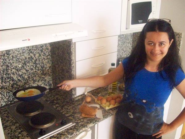 Woman cooking eggs in a frying pan, granite counter with eggs and bread