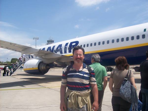 Smiling man in striped shirt in front of a Ryanair plane on the tarmac