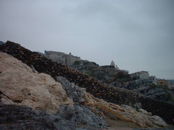 Light and dark boulders under grey sky, fortress and dome above the houses