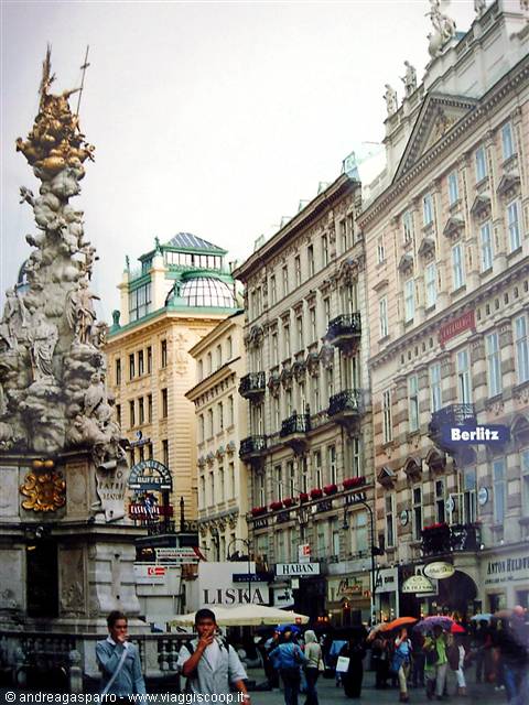 Plague Column on Vienna's Graben, pedestrians with umbrellas among historic buildings