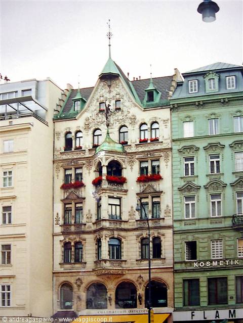Art Nouveau building with green oriels and roof, red flowers on windows