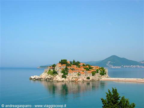 Sveti Stefan islet with stone houses, red roofs, calm blue sea and mountains
