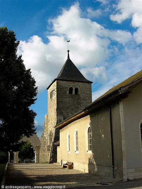 Romanesque stone bell tower beside Spiez church under white clouds