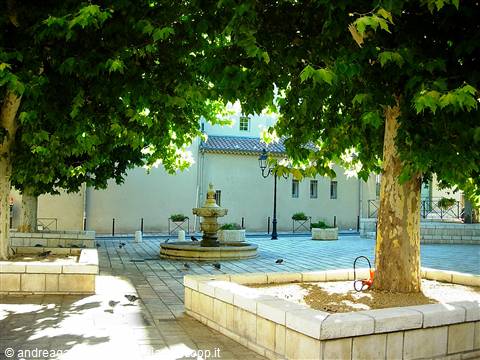 Shaded square with plane trees, stone fountain and white building