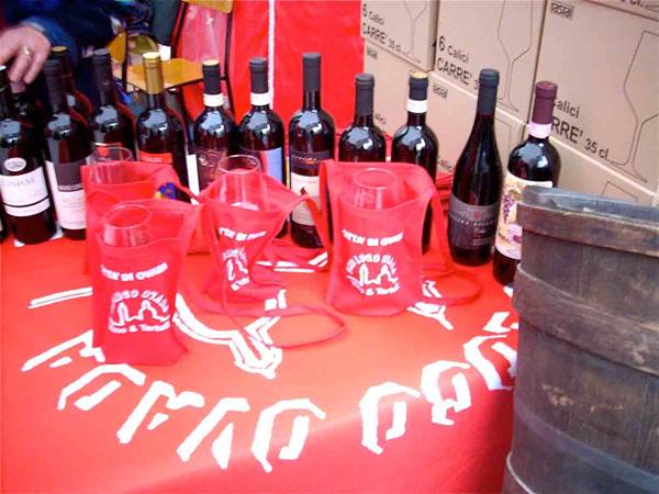 Red wine bottles on a red-clothed table with a wooden barrel