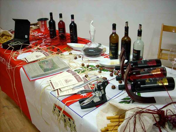 Table crowded with red wine bottles, decanter and brochures in a tasting room