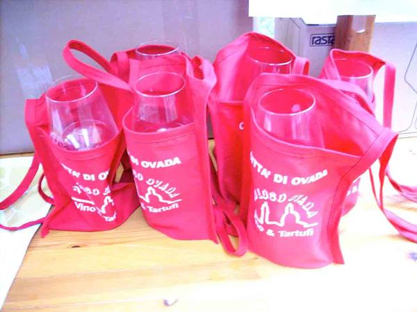 Red fabric bags holding wine glasses for the Ovada festival