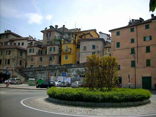 Roundabout with bushes in front of colorful old buildings in an Italian town
