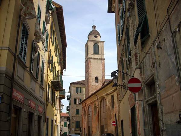 Old church bell tower between yellow and ochre houses, no-entry sign