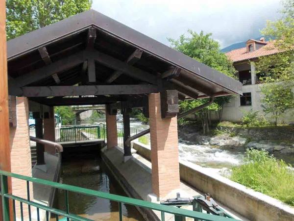 covered wooden-roof washhouse beside the rushing stream