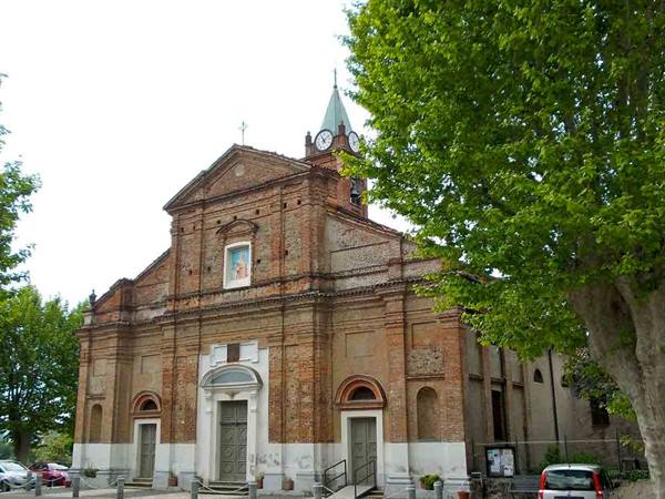 Brick church with clock bell tower, parked cars, green trees