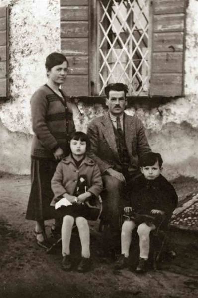 Family of four posing before rural house with wooden shutters, vintage photo