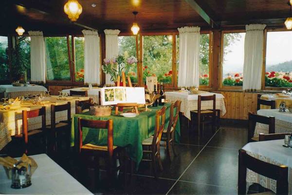 Restaurant dining room with set tables, green tablecloths and windows overlooking flowers
