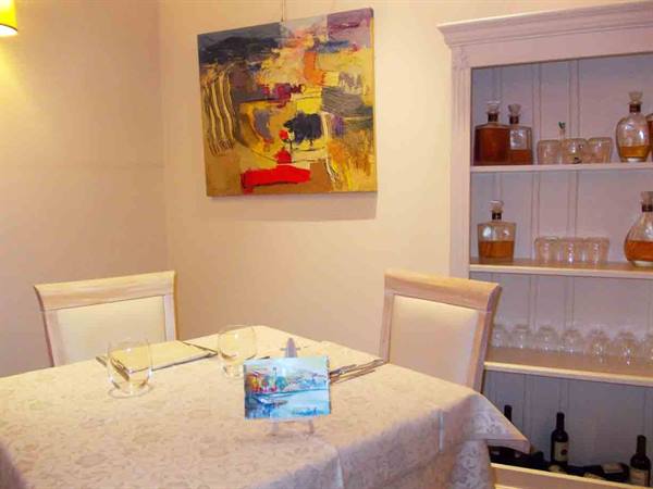 Set table with white tablecloth, abstract painting and cabinet with glasses