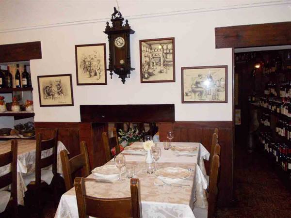 Trattoria dining room with set table, pendulum clock and framed prints