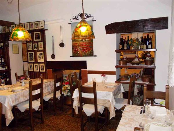 Trattoria dining room with set tables, lit Tiffany lamps and wine bottles