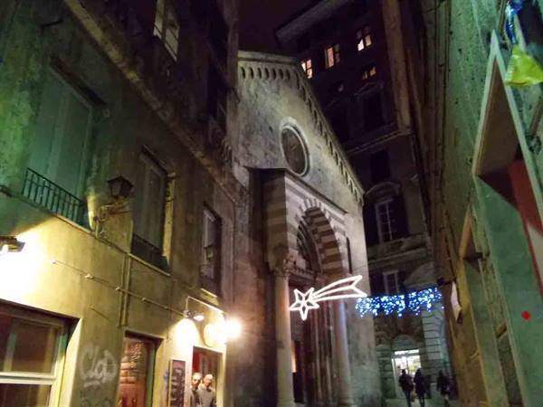 Night alley with striped marble church facade, Christmas lights in Genoa