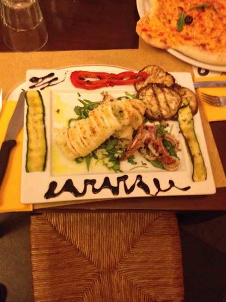 Grilled squid plate with zucchini, eggplant and arugula, pizza nearby
