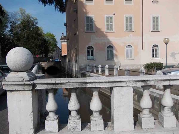 Stone balustrade with spherical finials over canal, pastel houses with shutters