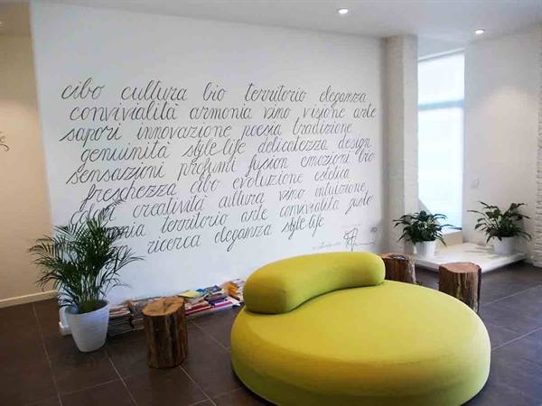 Round yellow sofa in front of calligraphy wall, potted plants nearby