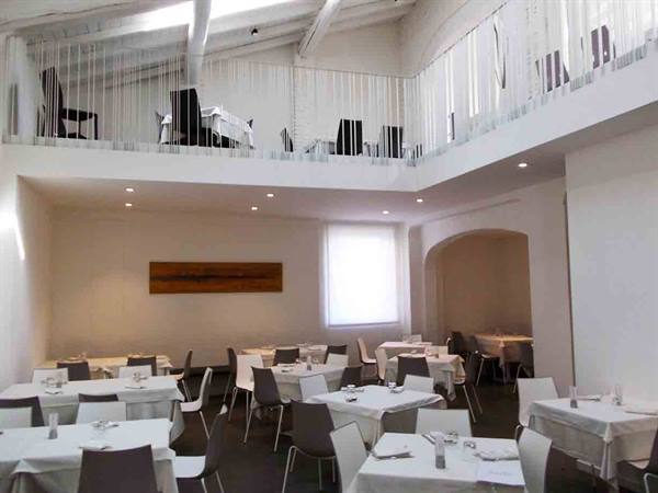Bright restaurant dining room with set tables, white beams and mezzanine