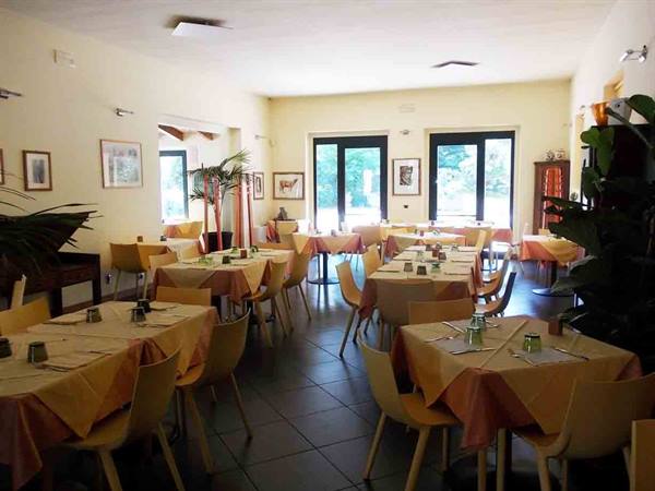 Empty restaurant dining room with set tables, orange tablecloths, plants and glass doors
