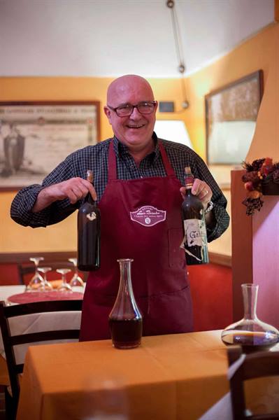 Smiling sommelier presenting two wine bottles in a restaurant